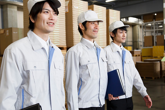 倉庫内に立っている作業着を着た3人の男性スタッフ